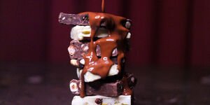 Close-up photo of a stack of brown and white chocolate, with molten chocolate poured on top