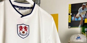 A close-up of a white football shirt with a white baseball cap in the background