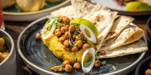 A close-up of a plate of food including folded flatbread and chickpeas
