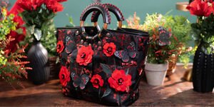 A photograph of a black handbag decorated with red leather flowers