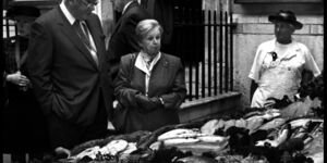 Black and white image of a woman laying flowers at a memorial.