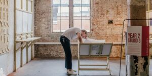 An image of a graduate working on his art piece in a studio.