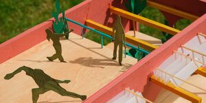 An art piece of paper figurines playing table football.