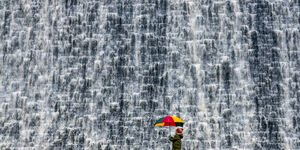 Image of a child holding an umbrella in front of a waterfall.