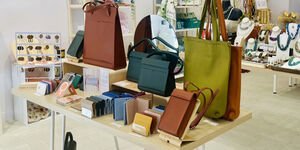 An interior of a shop with a table in the foreground, with leather bags displayed on it