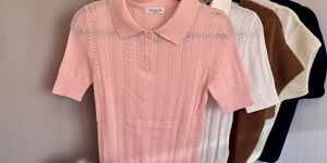 A pink knitted polo shirt hanging on a rail