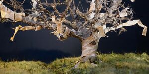An image of a tree onstage with a dark background.