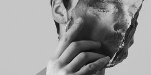 Image of a man holding up a clay mask.