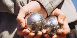 Image of someone holding two boules in their hand.