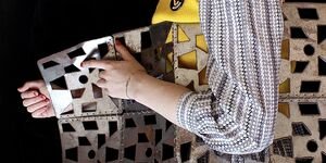 Photo of a woman holding up metallic art.