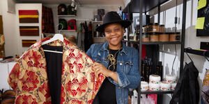 Image of Mariatu holding up clothing in her shop.