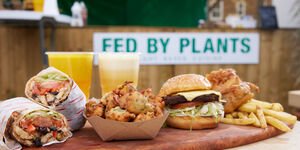 A photo of a wooden platter on top of which sits various food items including a burger