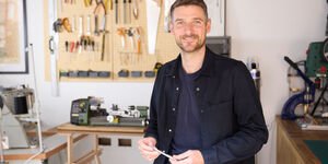 Image of Alasdair in his studio holding a pen.