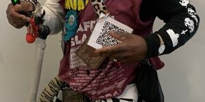 Davidstar standing holding a small traffic light and a QR code, wearing a flat cap and plastic glasses with a plastic nose attached