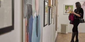 Image of a woman taking a photo of an art piece in a gallery.