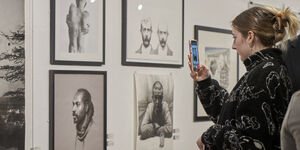 Image of a woman taking a photo of an art piece in a gallery.