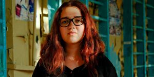 Image of a young girl with brown hair and glasses looking at the camera.