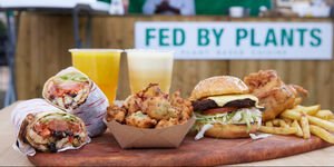 A wooden tray laden with food including a burger, chips and wrap