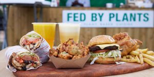 A selection of food including a buger and chips atop a wooden board