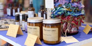 A shop shelf with candles in brown jars and a pile of fabric hair scrunchies