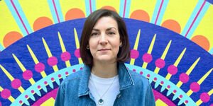 An image of Gina standing if front of her artwork at Bargehouse.