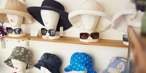 A selection of hats are displayed on wooden heads