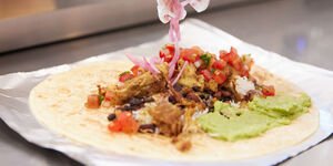 A close-up photo of a tortilla with meat and guacamole spread on top