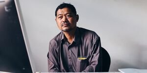 Image of a man sat at a computer in Cambodia.