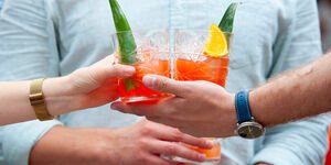 A photo of two people holding glasses of Rum Punch.