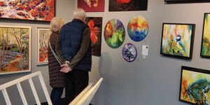 Image of an elderly couple looking at paintings at an art fair.