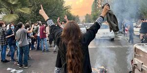 Image of a woman taking off her headscarf at a protest.