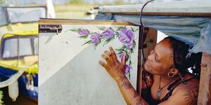 Image of a woman pointing to a painting of flowers.