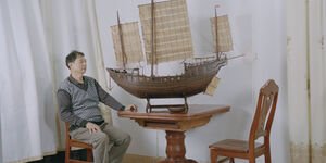 Image of a man sat with a wooden ship.