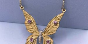 Image of a small gold butterfly necklace.