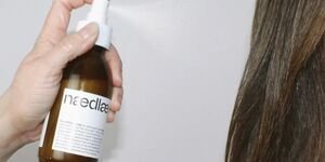 Image of someone spraying a hair product on hair.