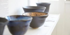 Five ceramic bowls sit on a white shelf