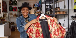 A woman holds up a red and gold coloured robe