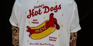 A man modelling the t-shirt with a dark background.