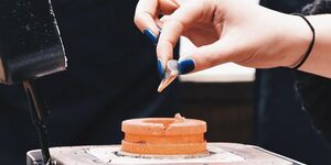 A hand holding a ring in the making.