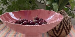 An image of a pink ceramic bowl containing cherries.
