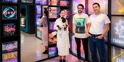 An image of Locomocean standing in front of their neon signs.