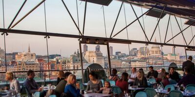 An image of people eating inside Oxo Tower Restaurant with London's skyline in the background.