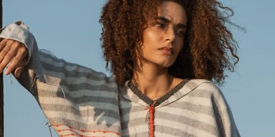 Image of a woman posing in beige trousers and a jumper.