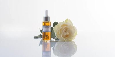 Image of a skincare serum next to a white rose.