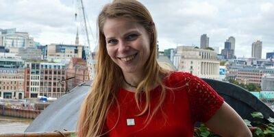 Andrea, hand on hip, smiling on the Oxo tower balcony with the river thames in the background