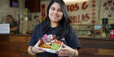 Image of Margarita holding nachos in her shop.