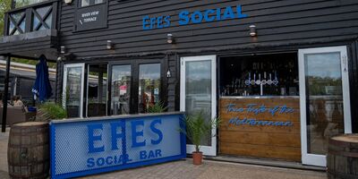 The outside of a wooden-clad building with a large blue sign reading EFES Social