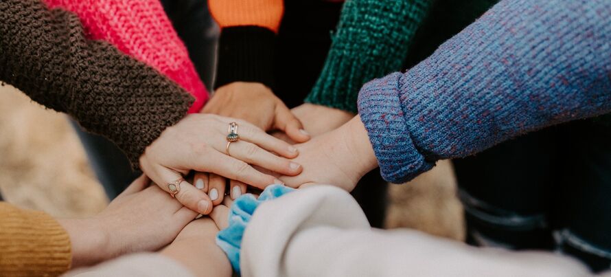 An image of a group of people joining their hands together in a group.