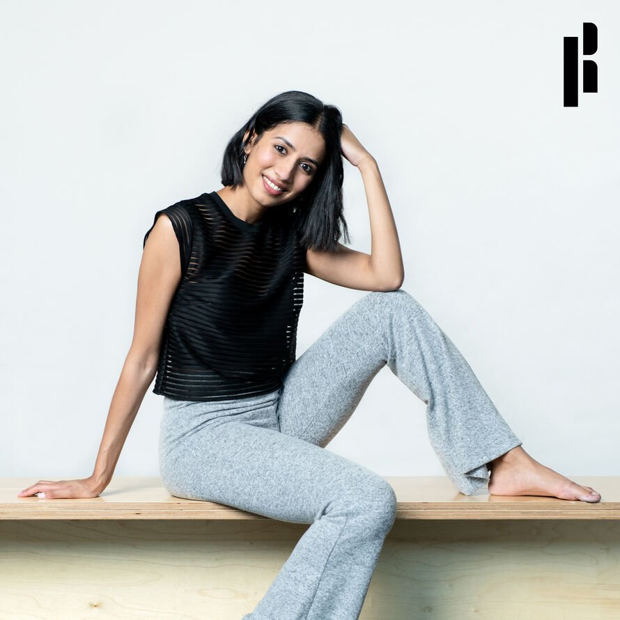 Picture of Priyanka posed on a bench, smiling at the camera