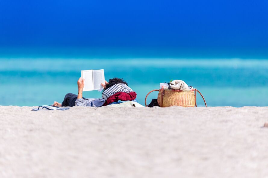 Image of someone reading a book by the beach.